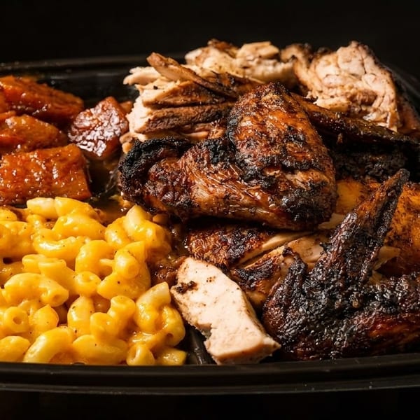 A black takeout container filled with grilled chicken, macaroni and cheese, and candied yams.